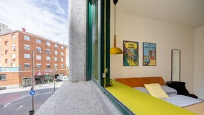 A hotel room with a large window, a bed with a yellow headboard, and two posters on the wall. - Central Flat Next to Gran V a Work or Study (Madrid)