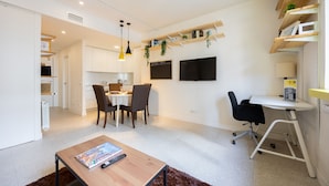 A modern living room with a dining area, a workspace, and built-in shelves with plants. - Central Flat Next to Gran V a Work or Study (Madrid)
