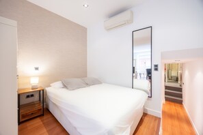 Une chambre à coucher comprenant un lit, une table de chevet, une lampe et un appareil de climatisation.