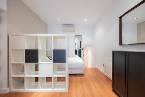Une chambre moderne avec un lit blanc, une armoire intégrée et un grand miroir.