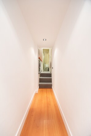 A narrow hallway with wooden flooring and white walls, leading to a staircase with a door at the top. - Studio in Barrio de las Letras Work or Study (Madrid)