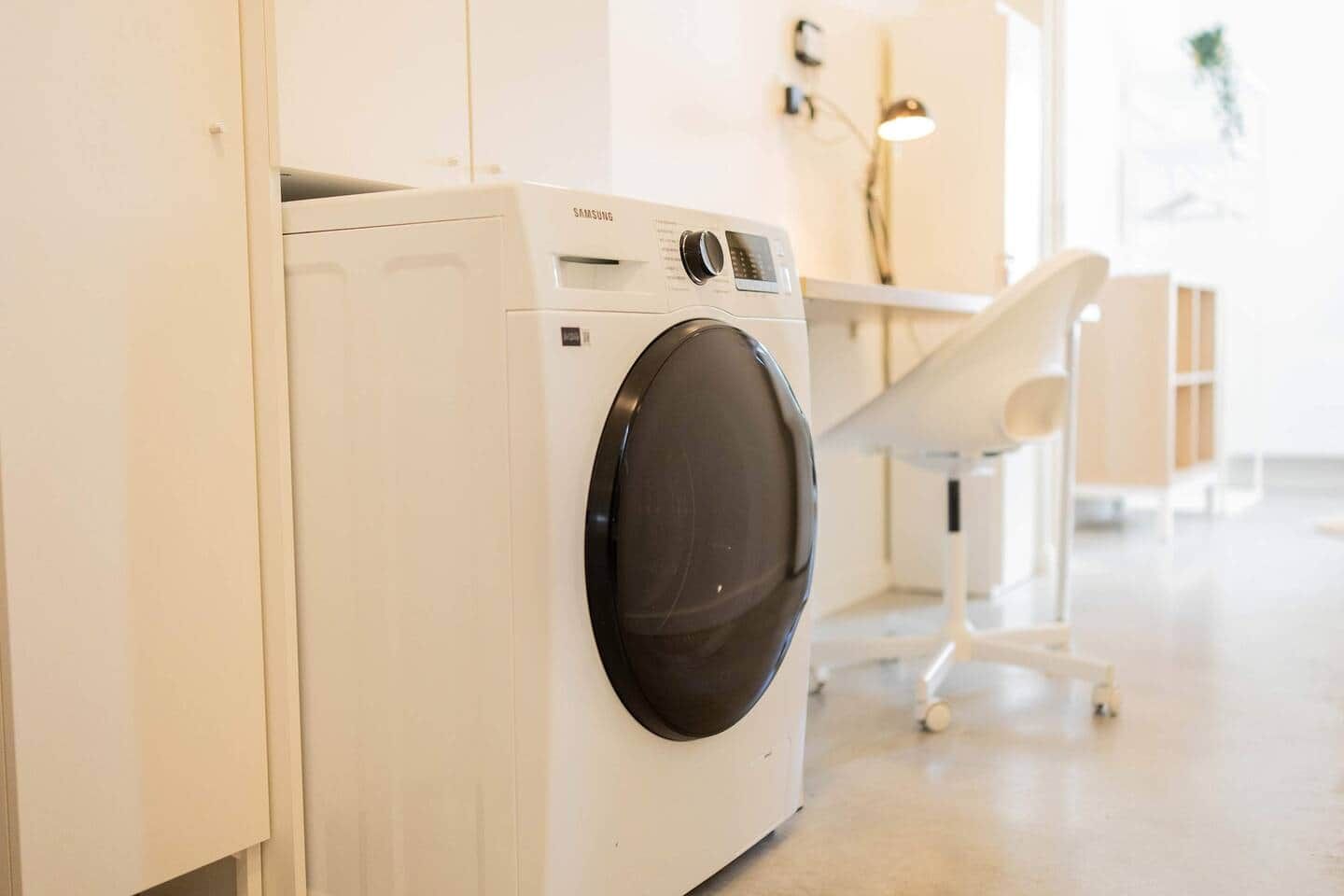 Een witte Samsung wasmachine in een lichte, moderne wasruimte met een minimalistisch design.