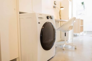 Une machine à laver Samsung blanche, dans une buanderie moderne et lumineuse, au design minimaliste.