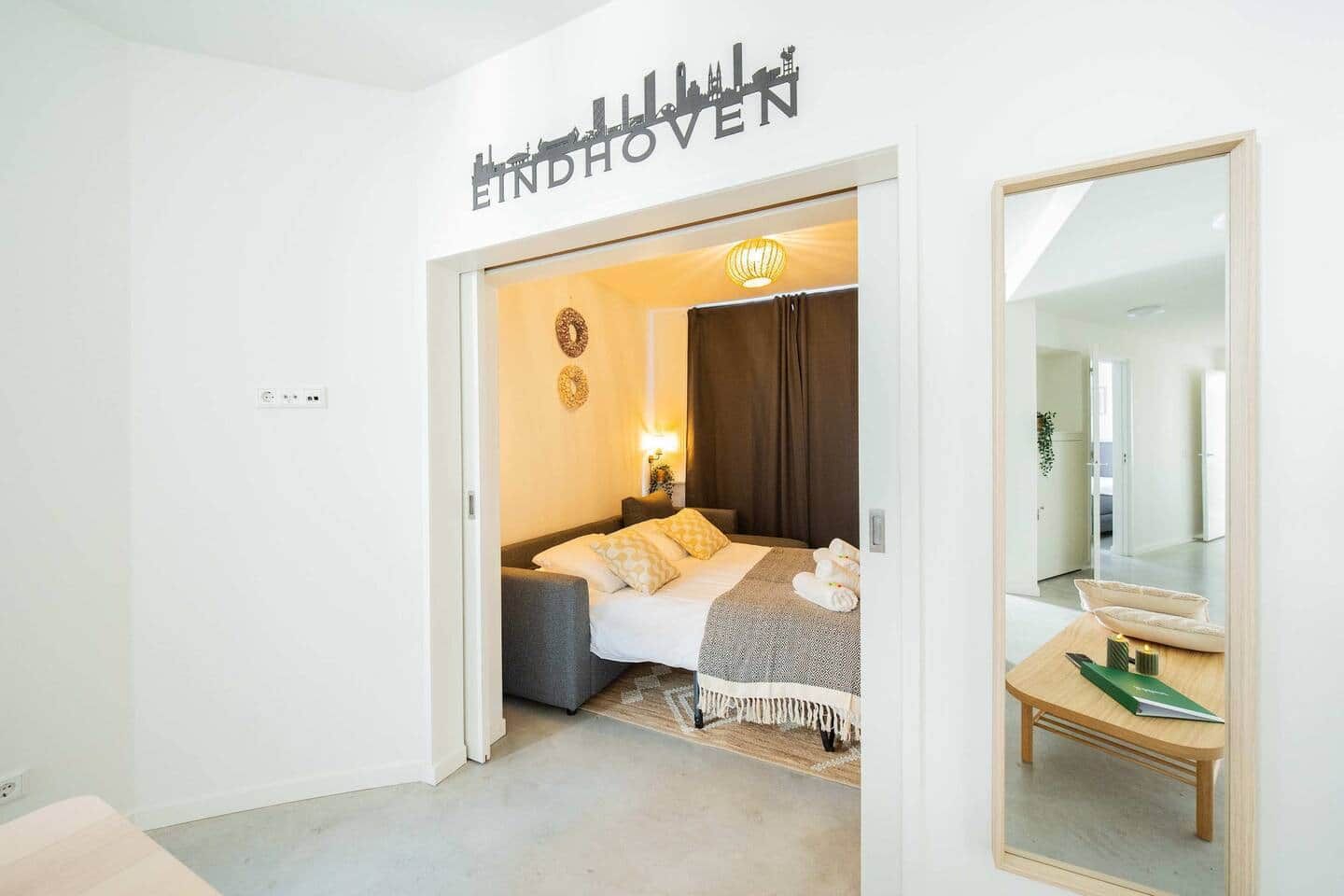 Une chambre d’hôtel avec un lit, une table de chevet et un miroir.