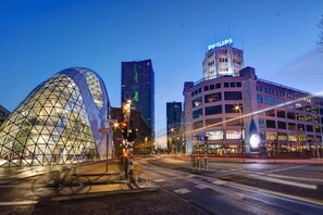 Un paysage urbain moderne avec une structure géodésique en forme de dôme remarquable, un immeuble de grande hauteur orné d’un panneau Philips et un bâtiment à plusieurs étages doté d’une enseigne lumineuse.