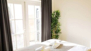 Una habitación de hotel con una cama, una ventana con cortinas y una planta en maceta.