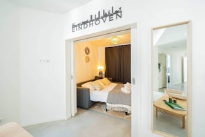 Hotellihuone, jossa on sänky, yöpöytä ja peili.