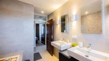 Een moderne badkamer met twee wasbakken, een spiegel en een douche.