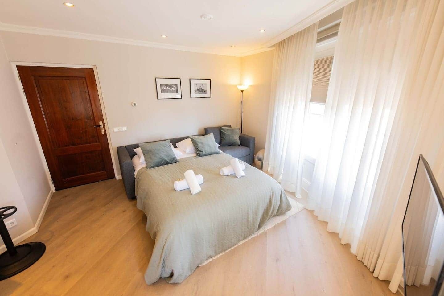 A bedroom with a bed, a bedside table, a lamp, a wardrobe, and a door.