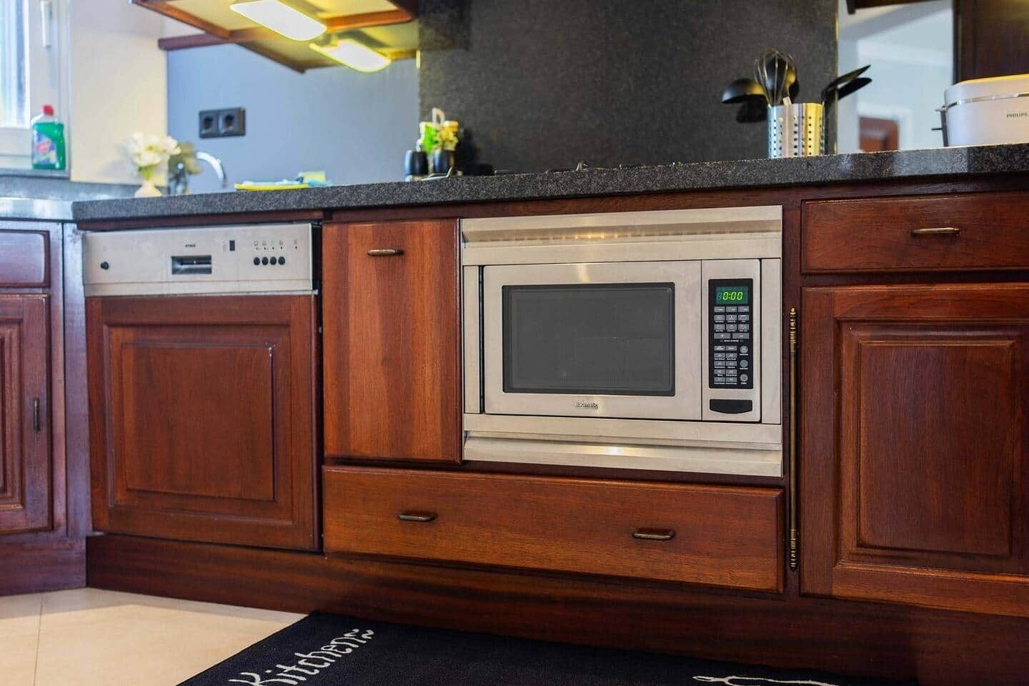 Une cuisine équipée d’un four à micro-ondes encastré, de meubles en bois et d’un lave-vaisselle.