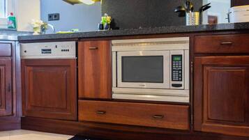Une cuisine équipée d’un four à micro-ondes encastré, de meubles en bois et d’un lave-vaisselle.