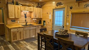 Una cocina tipo cabaña con armarios de madera, un lavamanos y un comedor con mesa y sillas.