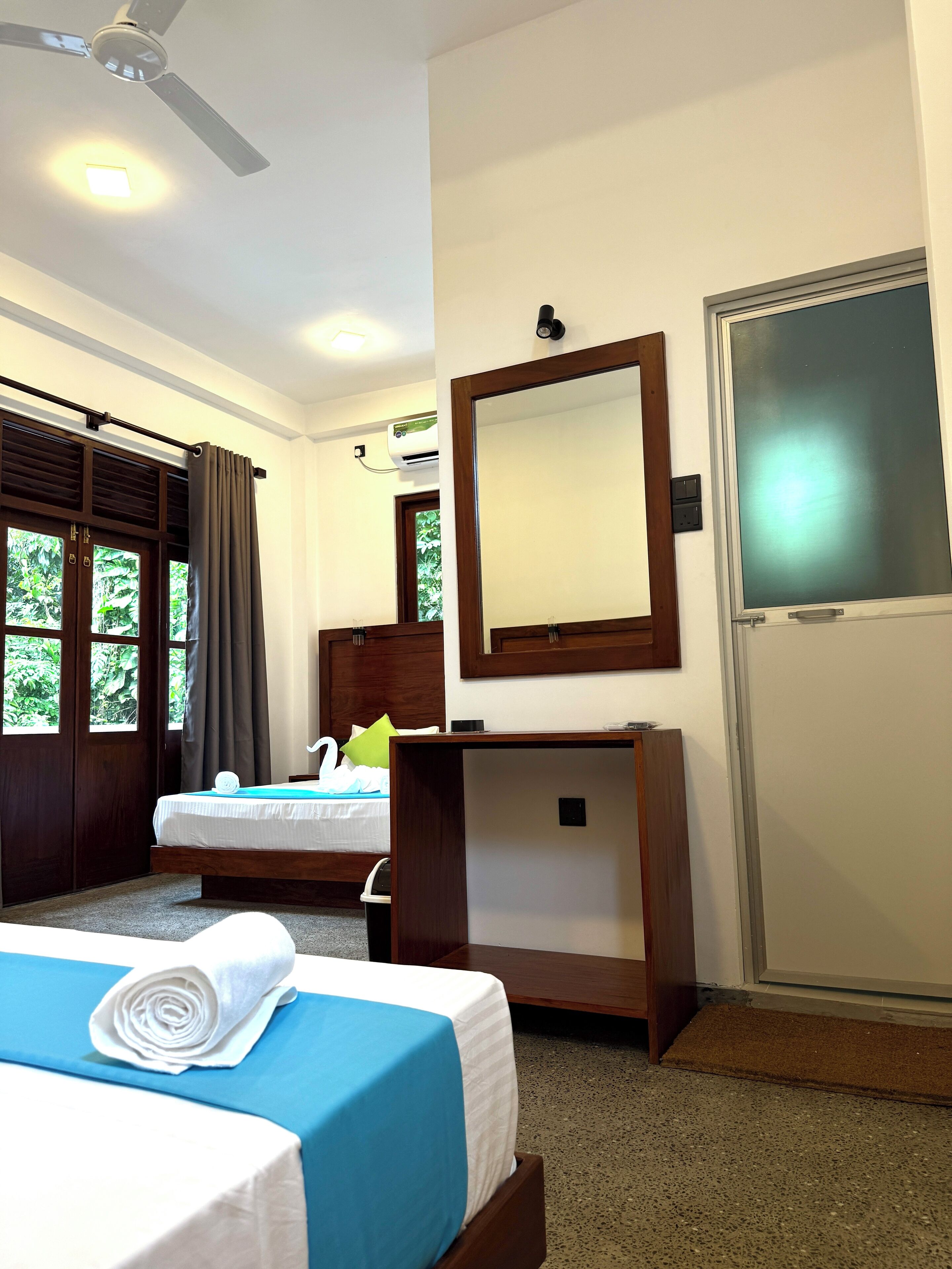 A hotel room with a bed, a desk, a mirror, and a door.