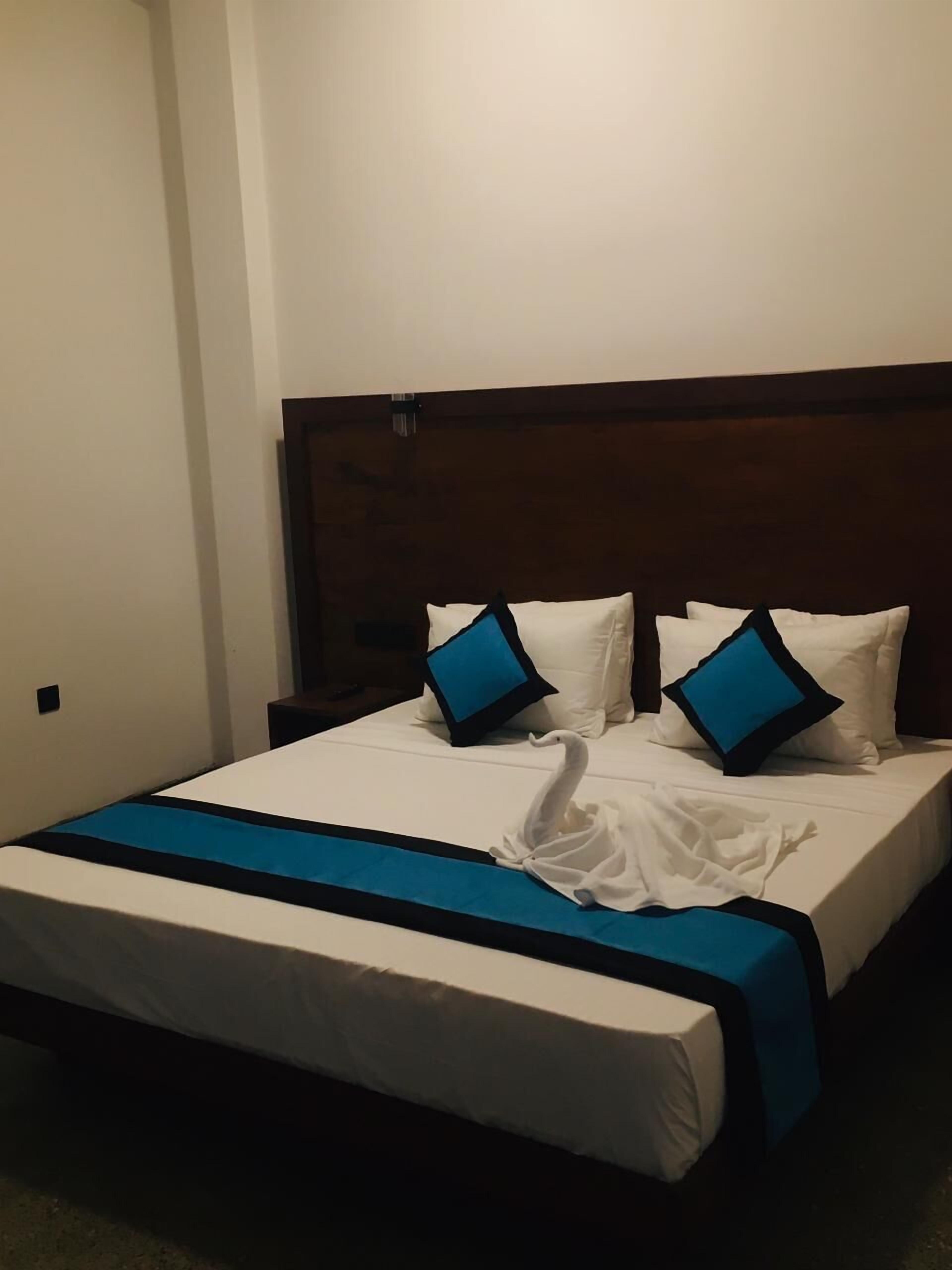 A hotel room with a large bed, white bedding, and blue pillows.