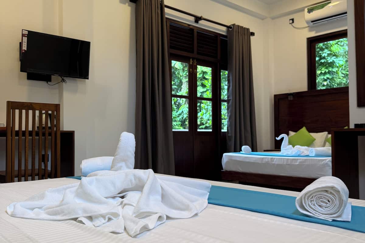 Une chambre d’hôtel avec un lit, un bureau, une chaise, une télévision et une fenêtre avec des rideaux.