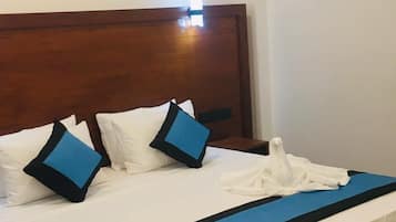 A hotel room with a wooden headboard, a white bedspread, and blue accents on the pillows and bed skirt.