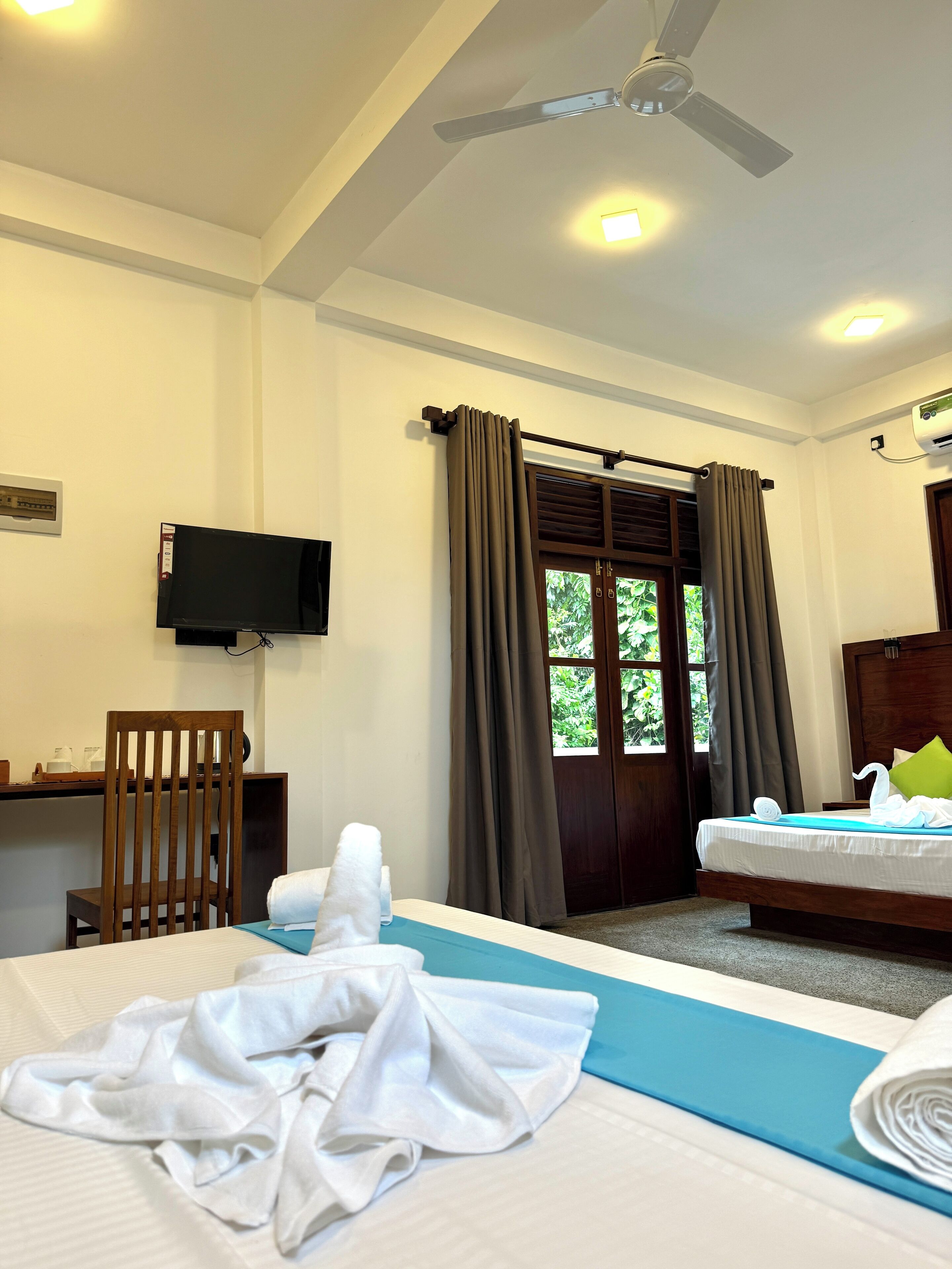 A hotel room with a bed, a desk, a chair, a television, and a window with curtains.