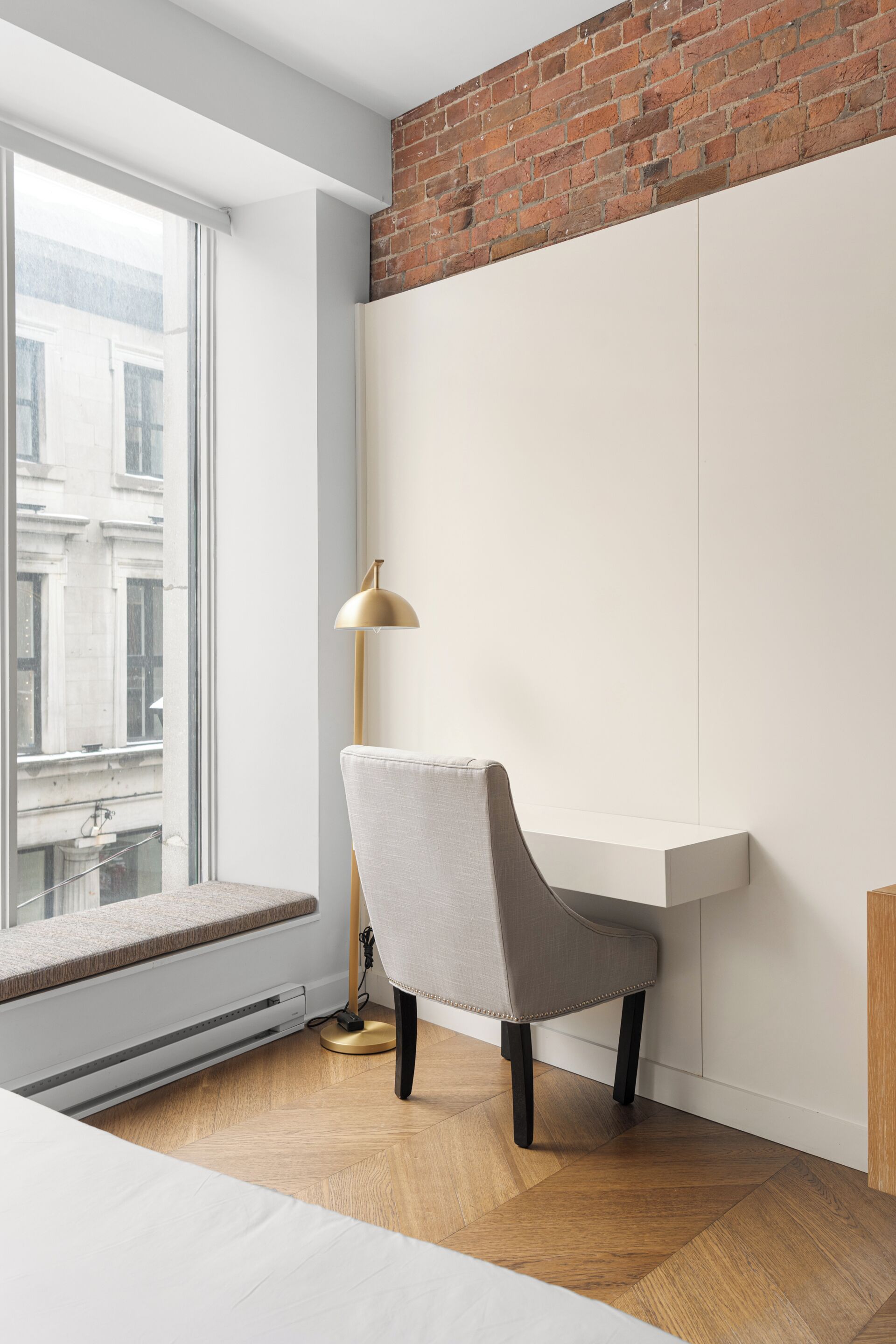 Quarto moderno com uma janela grande, um banco embutido, uma escrivaninha e um abajur.