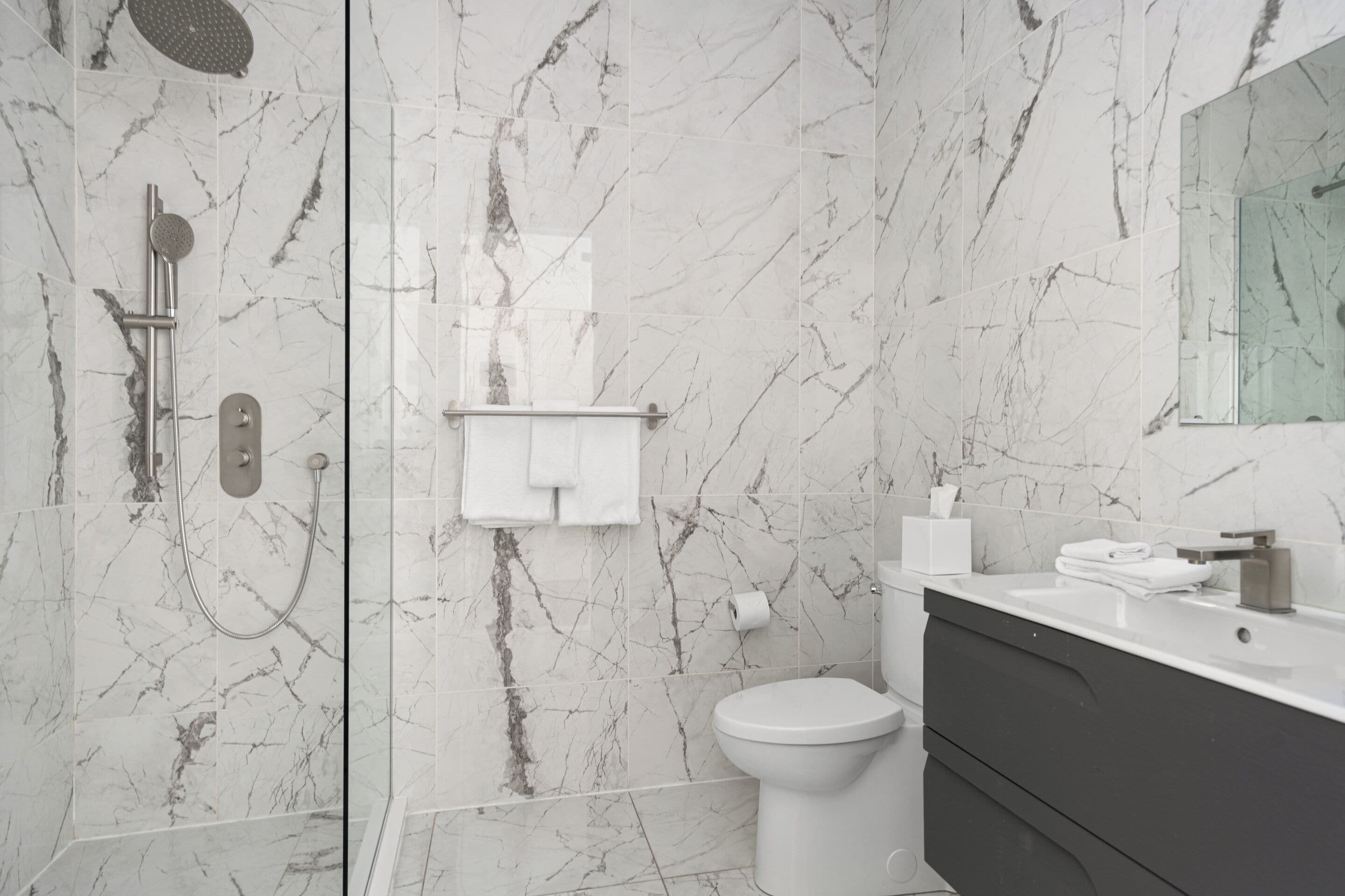 Un baño moderno con ducha, inodoro y tocador.