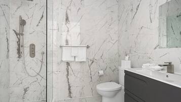 Un baño moderno con ducha, inodoro y tocador.
