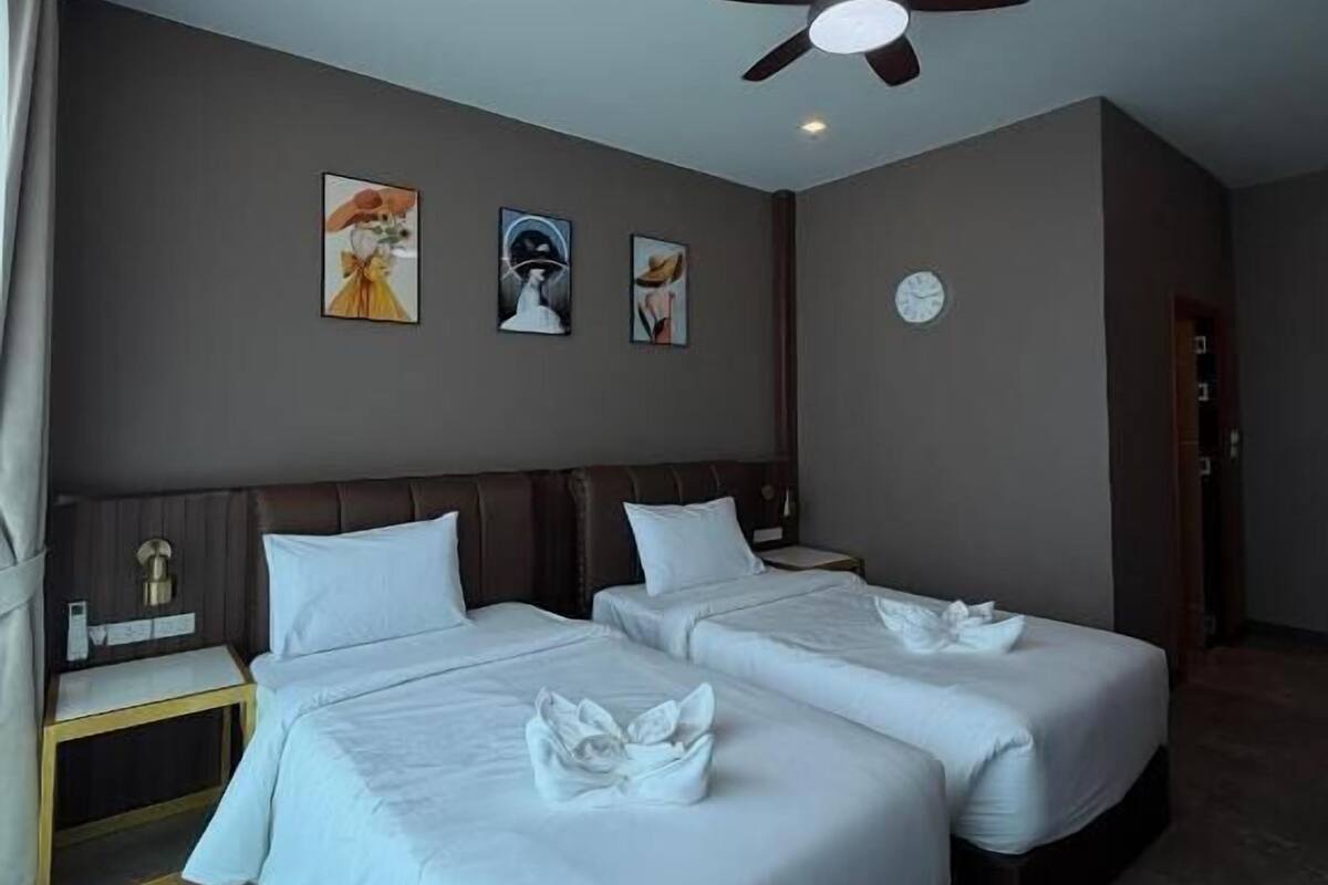 Ein Hotelzimmer mit zwei Betten, einem Deckenventilator und Bildern an den Wänden.