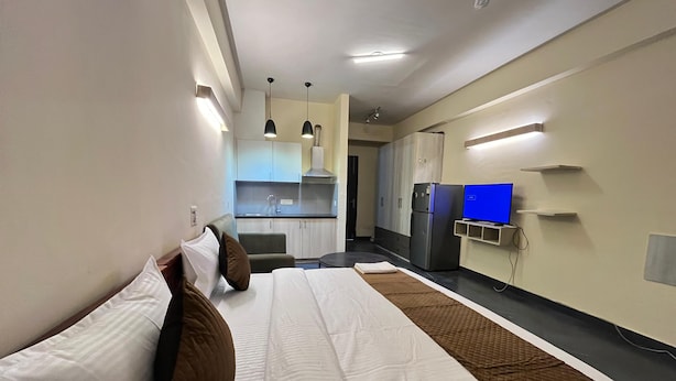 A hotel room with a bed, a small kitchenette, a TV, and a desk. - GoBravo Residences – Kapashera, New Delhi (New Delhi)