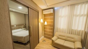 Une chambre d’hôtel équipée d’un lit, d’un canapé, d’un climatiseur et d’une lampe.
