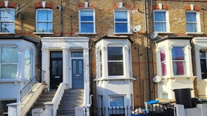 A row of terraced houses with a central staircase leading to the entrance. - Modern 2BR London Apt Near Tube (Greater London)