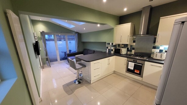 A modern kitchen with a central island, a stove, oven, and a refrigerator. - Large 4 Bedroom House In Central London (Greater London)