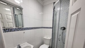 A bathroom with a white sink, toilet, and glass-enclosed shower. - Tooting Bec Central Apartment by London Tube (Tooting Bec, London)