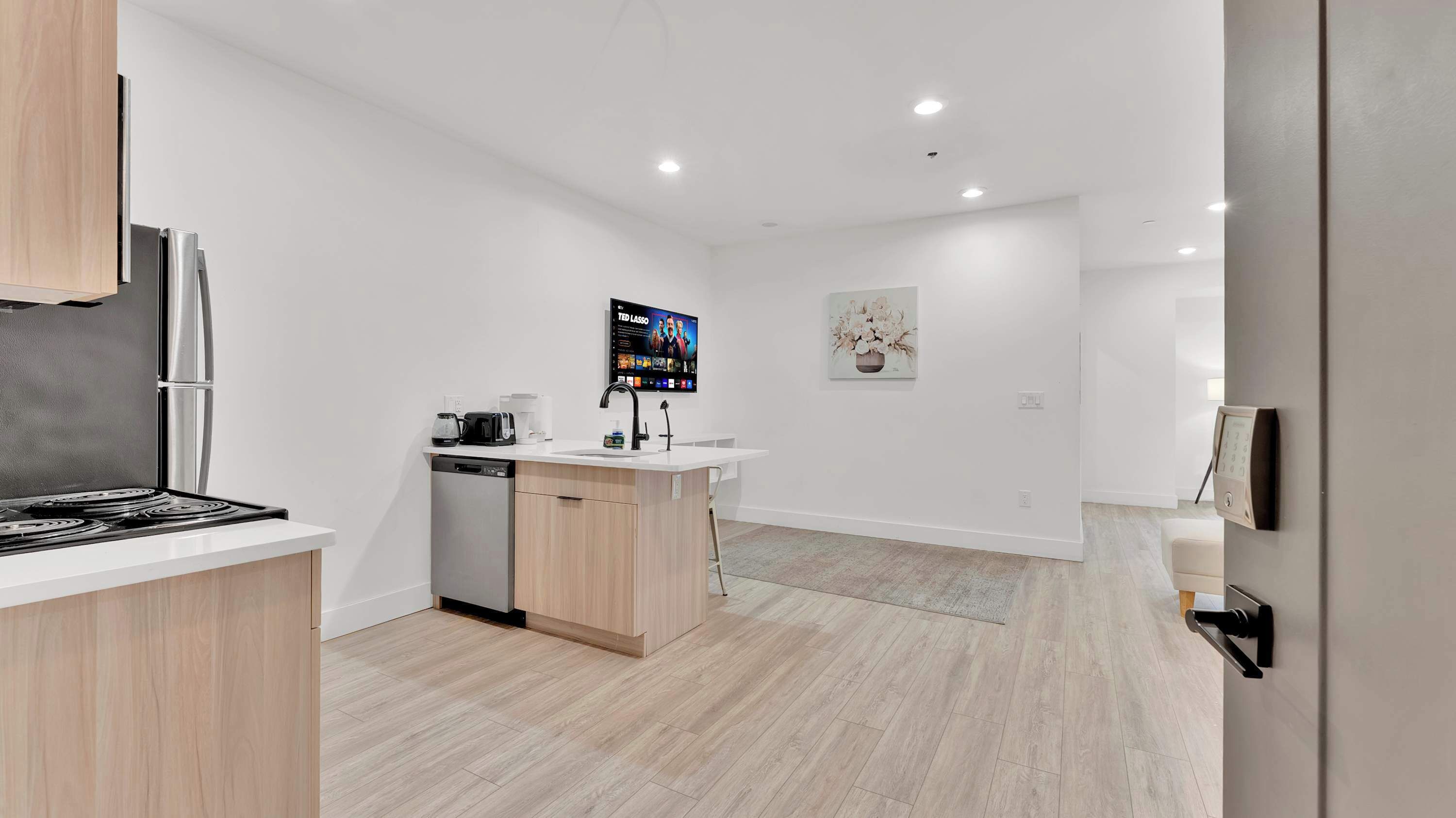 A modern kitchen with a dishwasher, stove, and a coffee maker.