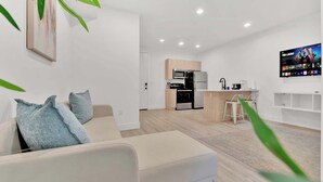 Ein modernes Wohnzimmer mit einer Couch, einem Couchtisch und einem an der Wand befestigten Fernseher.