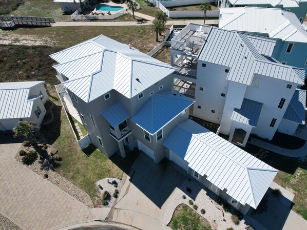 A multi-story residential building with a unique architectural design, featuring a combination of flat and sloped roofs, and a central courtyard with a swimming pool. - Salty Kisses | Private Pool, Ocean Views (Corpus Christi)
