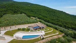 Une villa avec piscine, entourée d’une végétation luxuriante et située dans un paysage vallonné.