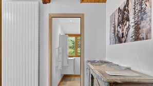 Un couloir avec un radiateur, une porte en bois et un tableau accroché au mur.