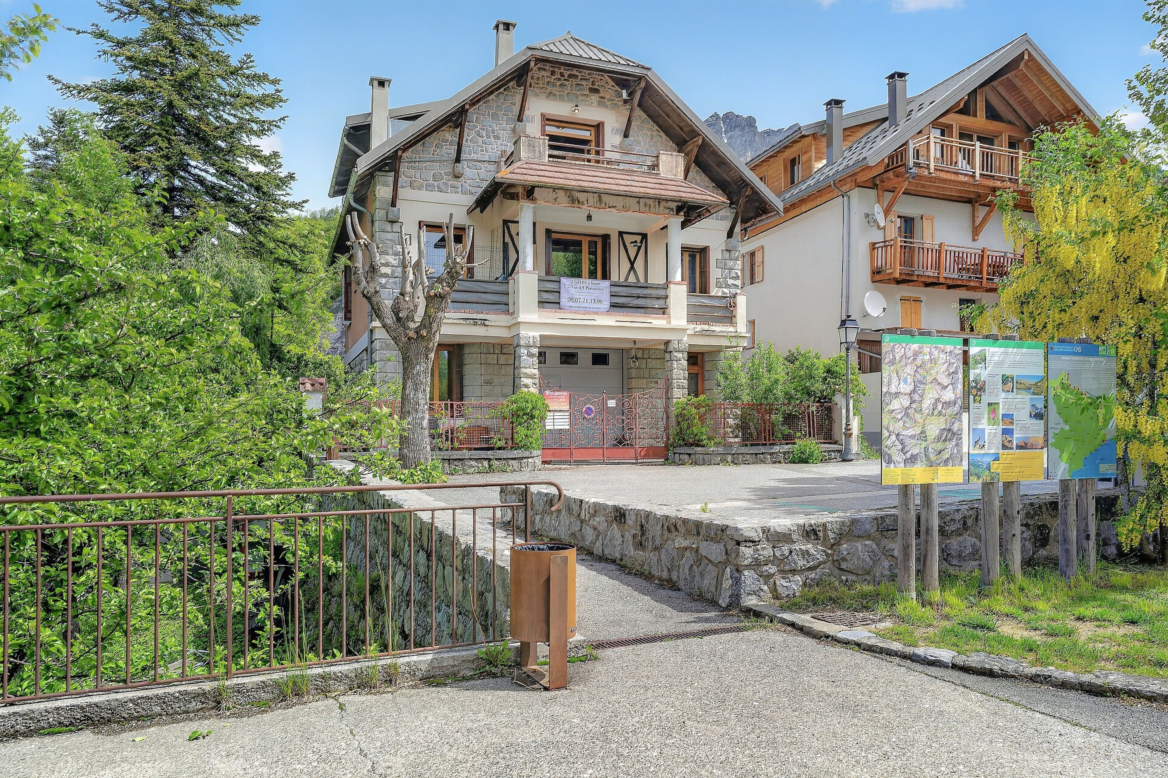 Ein traditionelles Chalet mit Steinaußenwand, hölzernen Balkonen und freiem Blick auf die umliegende Grünfläche.