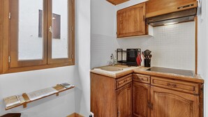 Una cocina con armarios de madera, una ventana y salpicadero de azulejos.