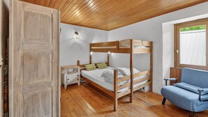 Una habitación con literas, una mesita, una silla y una ventana con vistas.
