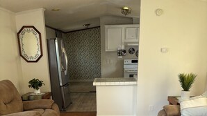 A living room with two brown sofas, a patterned rug, and a kitchen in the background. - Quiet Kentucky Retreat • Clean, Comfortable (Williamsburg)