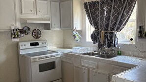 A compact kitchen with white cabinetry, a stove, and a sink. - Quiet Kentucky Retreat • Clean, Comfortable (Williamsburg)