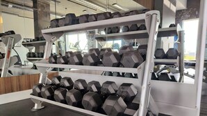 Ein Fitnessraum mit einer Hantelbank und einem Laufband.