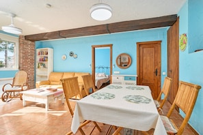 Un coin repas avec une table dressée pour quatre personnes, entouré de chaises en bois, d’un canapé et d’une bibliothèque.