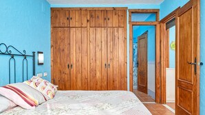 Ein Schlafzimmer mit Bett, Holzschrank und Tür zum Badezimmer.