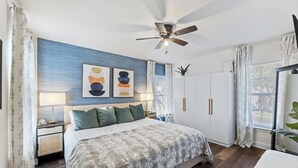 Une chambre à coucher comprenant un lit, des tables de chevet, un ventilateur de plafond et une armoire.