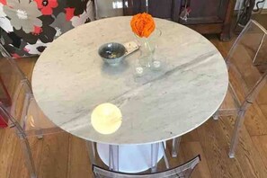 A round table with a marble top, a small bowl, and a vase with a single orange flower. - Charming Apartment on the Navigli (Milano)