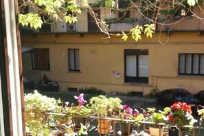 A courtyard with potted plants and outdoor furniture, reflecting a building with balconies and windows in the background. - Charming Apartment on the Navigli (Milano)