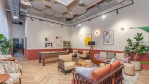 En rummelig lounge med flere siddepladser, herunder sofaer og lænestole, placeret omkring et sofabord i midten.