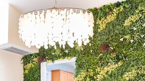A dining area with a wooden table and blue upholstered chairs, surrounded by a lush green vertical garden wall. - 5BR w/4 Kings•Pool•Fire Pit•BBQ Grill•Yard Games (Phoenix)
