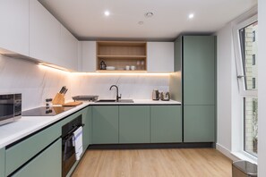 A modern kitchen with a built-in microwave, a sink, and a wooden countertop. - The Nest in Bristol with 2 bedrooms and 2 bathrooms (Bristol)