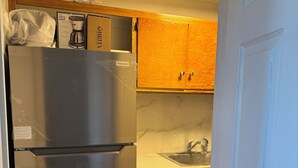 Een keuken met een roestvrijstalen koelkast, houten kastjes, een marmeren aanrechtblad en een spoelbak.